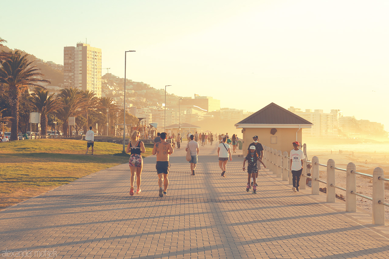 Sunset Stroll in the Mother City Foto von Joggers and walkers enjoy a golden sunset along Cape Town's breezy promenade.